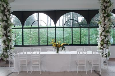 Salle de réception avec tables dressées, chaises noires, murs sombres et un buffet en arrière-plan.