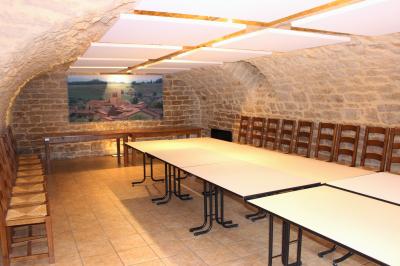 Salle lumineuse avec carrelage clair, baies vitrées, rangées de chaises empilées et un comptoir au fond.