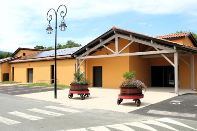Salle de réception avec tables dressées, décorées de feuillages et vaisselle, éclairée par de grandes baies vitrées.