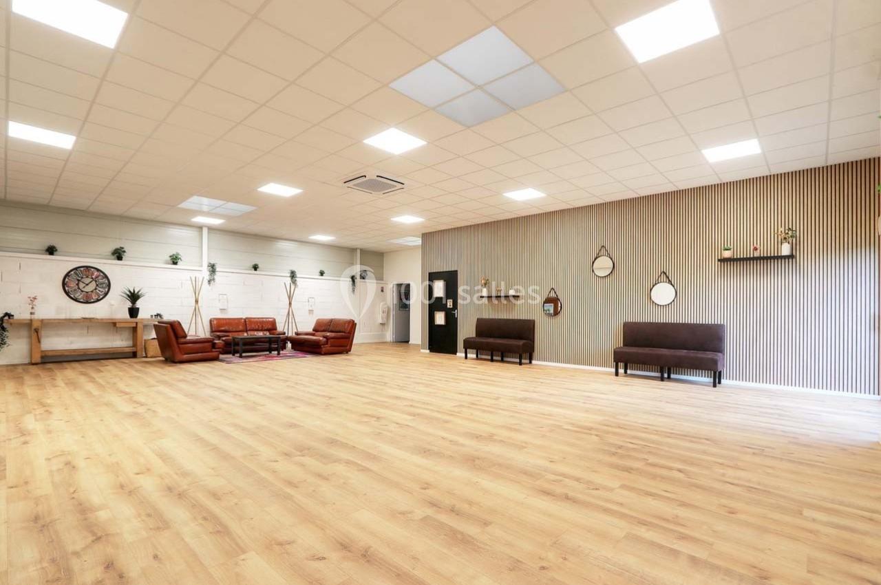 Salle spacieuse avec parquet clair, murs décorés de miroirs et étagères, mobilier minimaliste et lumière naturelle.