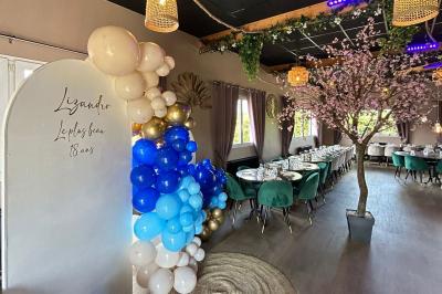 Salle de réception décorée avec des tables dressées et un buffet de cocktails sur une nappe blanche.