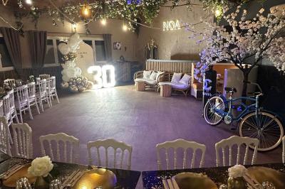 Salle de réception décorée avec des tables dressées et un buffet de cocktails sur une nappe blanche.