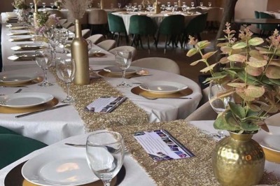 Salle de réception décorée avec des tables dressées et un buffet de cocktails sur une nappe blanche.
