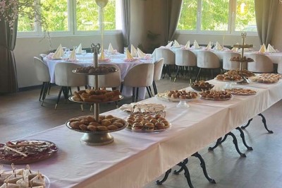 Salle de réception décorée avec des tables dressées et un buffet de cocktails sur une nappe blanche.