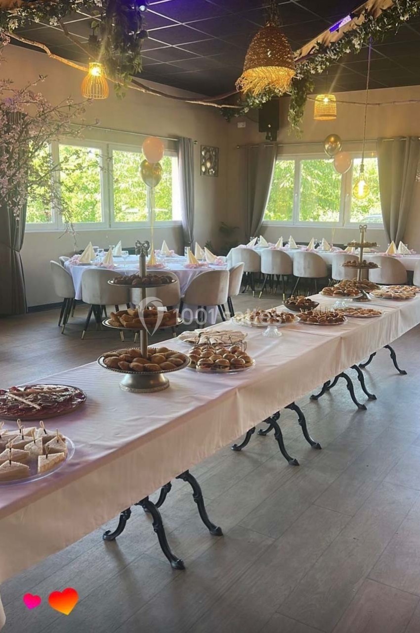 Salle décorée pour un événement avec une longue table garnie de pâtisseries et de desserts variés.