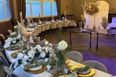 Salle de réception décorée avec des tables dressées et un buffet de cocktails sur une nappe blanche.
