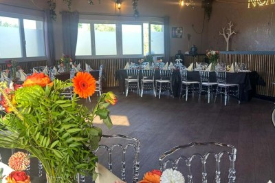 Salle de réception décorée avec des tables dressées et un buffet de cocktails sur une nappe blanche.