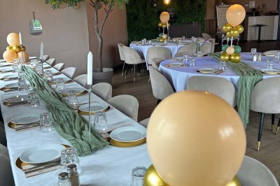 Salle de réception décorée avec des tables dressées et un buffet de cocktails sur une nappe blanche.