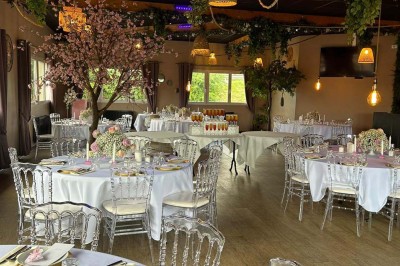 Salle de réception décorée avec des tables dressées et un buffet de cocktails sur une nappe blanche.