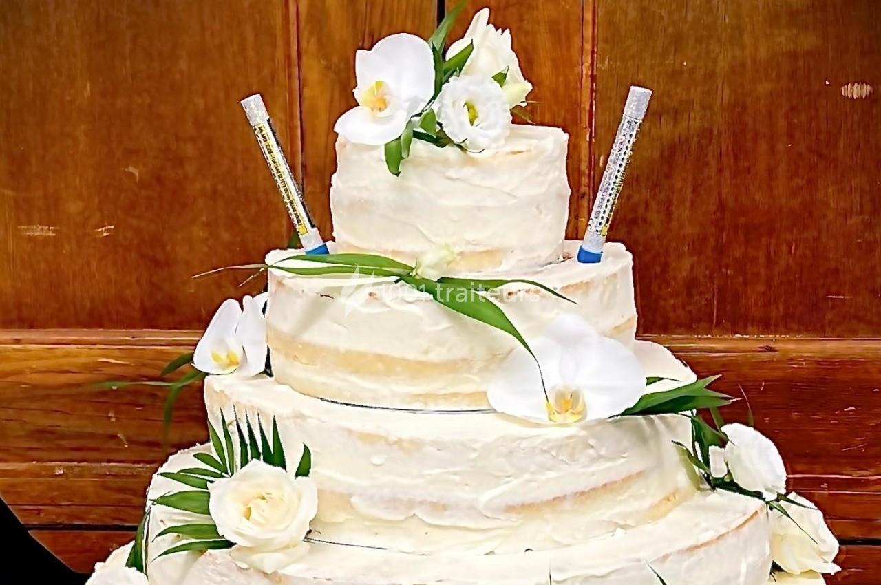 Gâteau de mariage à trois étages décoré de fleurs blanches et de seringues en guise d'éléments décoratifs.