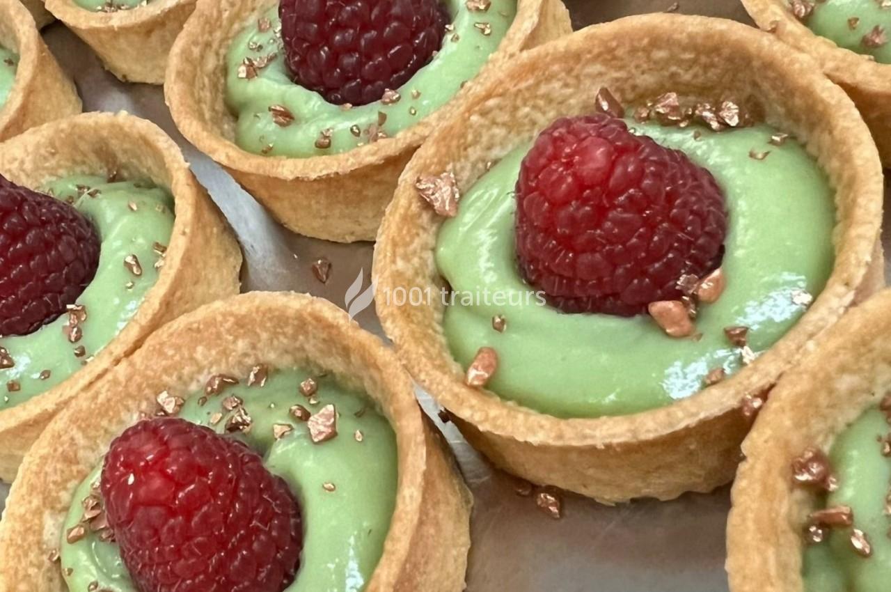 Tartelettes garnies de crème verte, décorées d'une framboise et de copeaux dorés.