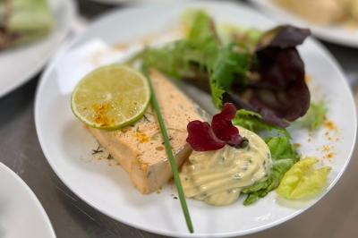 Plateau de charcuterie avec jambon, saucisson, cornichons, tomates cerises et feuilles de salade en décoration.