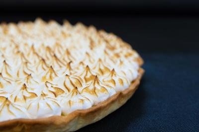 Plateau de charcuterie avec jambon, saucisson, cornichons, tomates cerises et feuilles de salade en décoration.