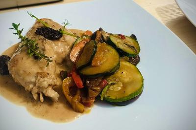 Plateau de charcuterie avec jambon, saucisson, cornichons, tomates cerises et feuilles de salade en décoration.