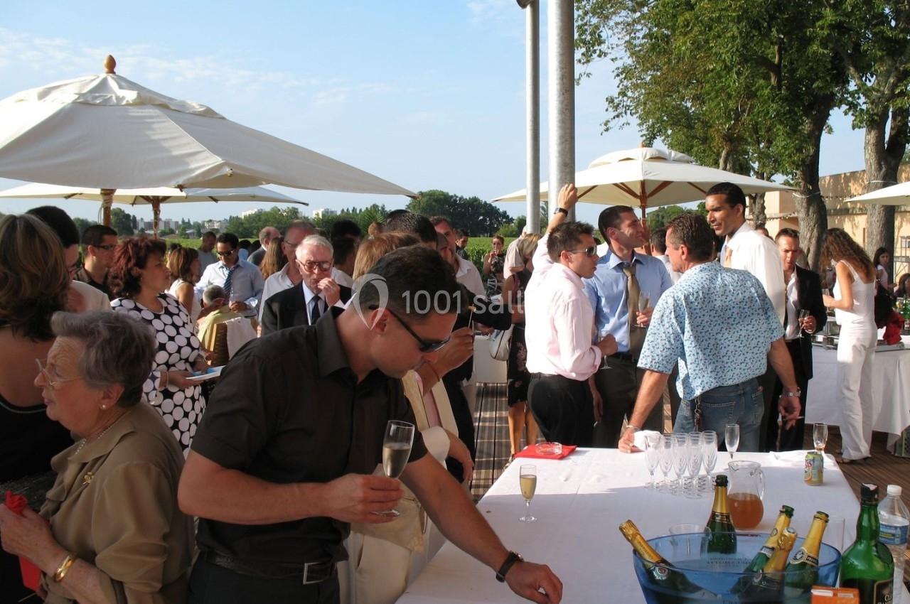 Groupe de personnes discutant et partageant un apéritif en extérieur sous des parasols par temps ensoleillé.