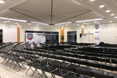 Un groupe de personnes échange autour d'un buffet en plein air, avec des serveurs et un paysage de vignoble en arrière-plan.