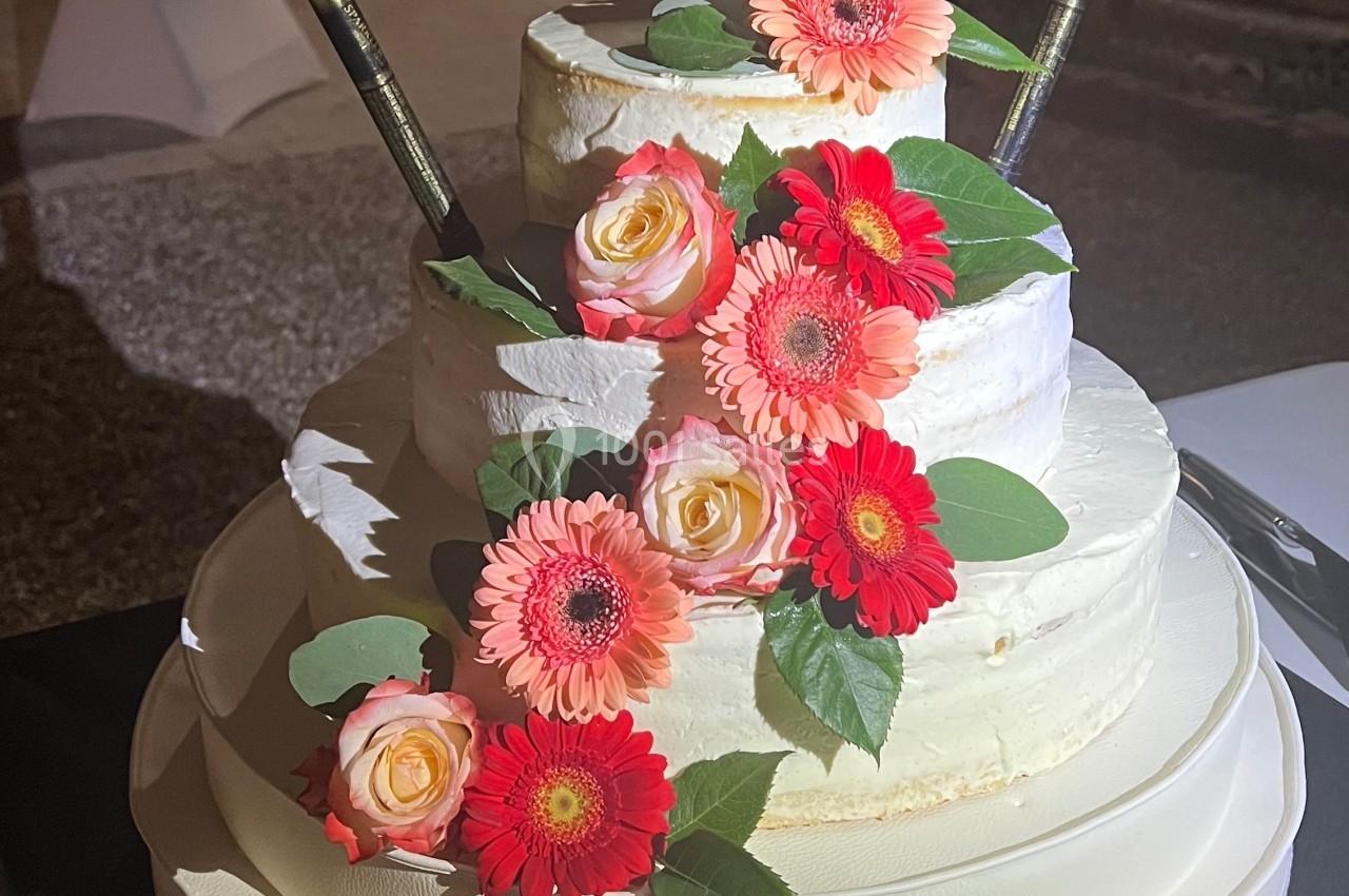 Gâteau de mariage à trois étages décoré de fleurs roses et oranges, avec un topper personnalisé ’Les Tillier’.
