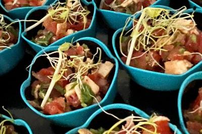 Plateau de charcuterie avec jambon, saucisson, cornichons, tomates cerises et feuilles de salade en décoration.