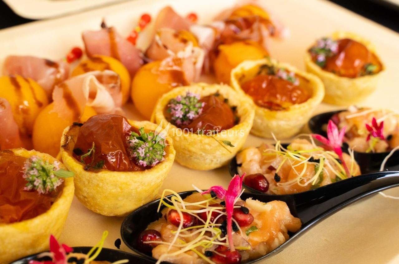 Assortiment de bouchées apéritives comprenant tartelettes, brochettes de melon et cuillères de tartare décorées.