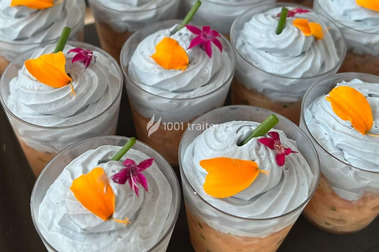 Verrines garnies de mousse grise, décorées de fleurs comestibles orange et violettes.