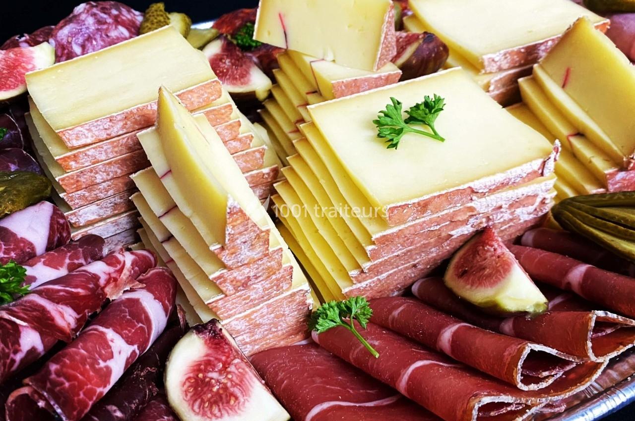 Plateau de charcuterie et fromages avec tranches de jambon, salami, fromage empilé, figues fraîches et cornichons.