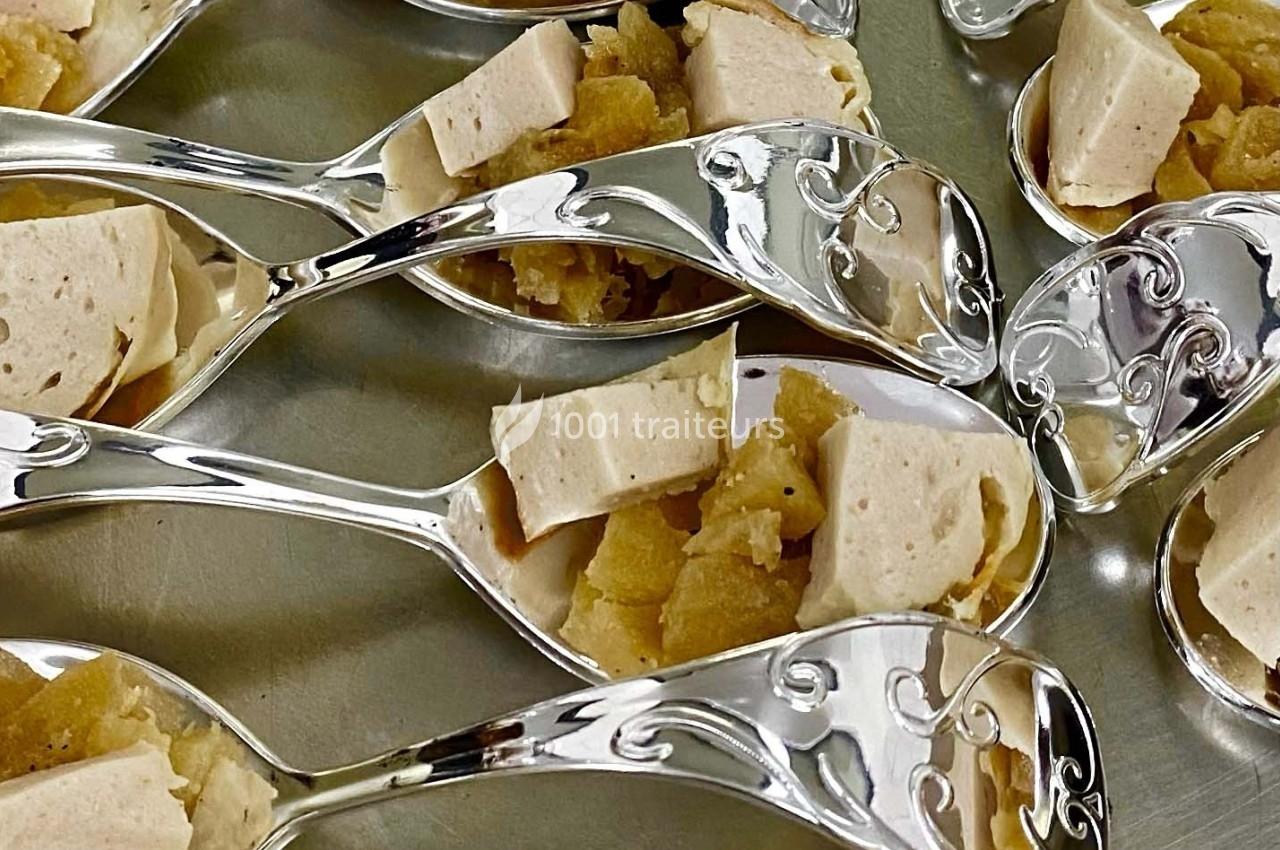 Cuillères en métal décoré contenant des morceaux de tofu et une garniture dorée sur une surface argentée.