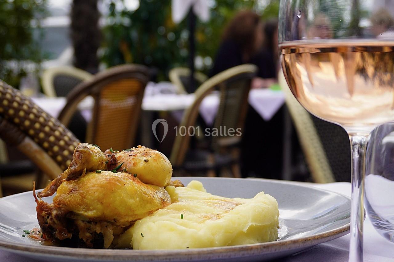 Assiette de poulet rôti avec purée de pommes de terre, servie en terrasse avec un verre de vin rosé au premier plan.
