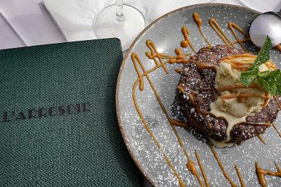 Dessert au chocolat avec glace vanille, caramel et menthe, présenté sur une assiette à côté d'un menu vert.