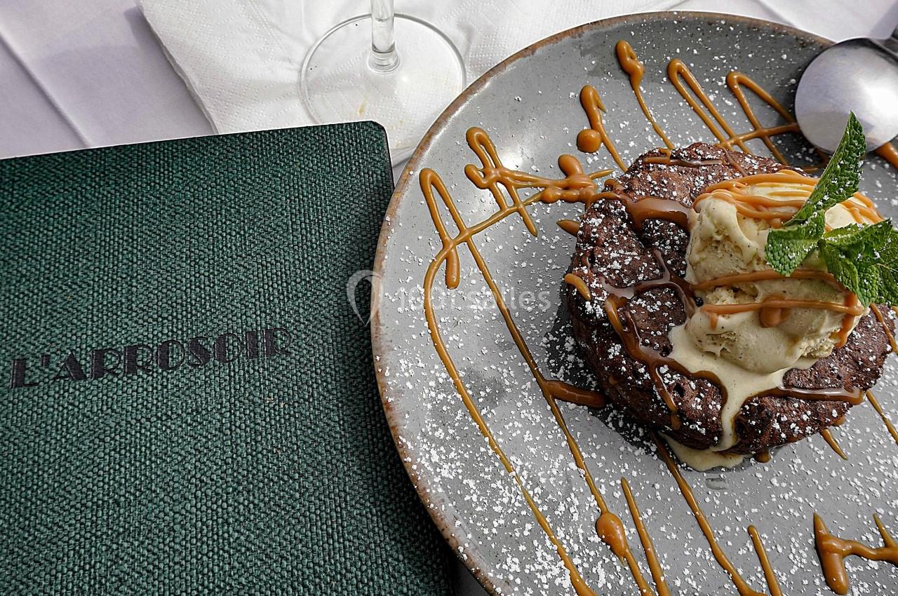 Dessert au chocolat avec glace vanille, caramel et menthe, présenté sur une assiette à côté d'un menu vert.