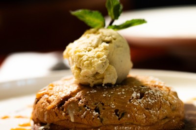 Dessert composé d'un biscuit chaud garni de glace à la vanille, décoré de chocolat et caramel, avec un verre de vin…