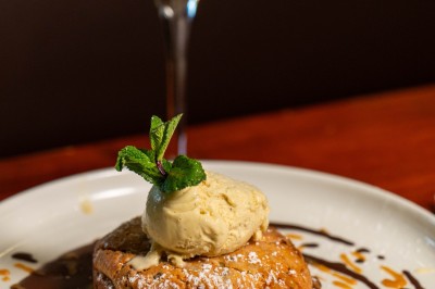 Dessert composé d'un biscuit chaud garni de glace à la vanille, décoré de chocolat et caramel, avec un verre de vin…