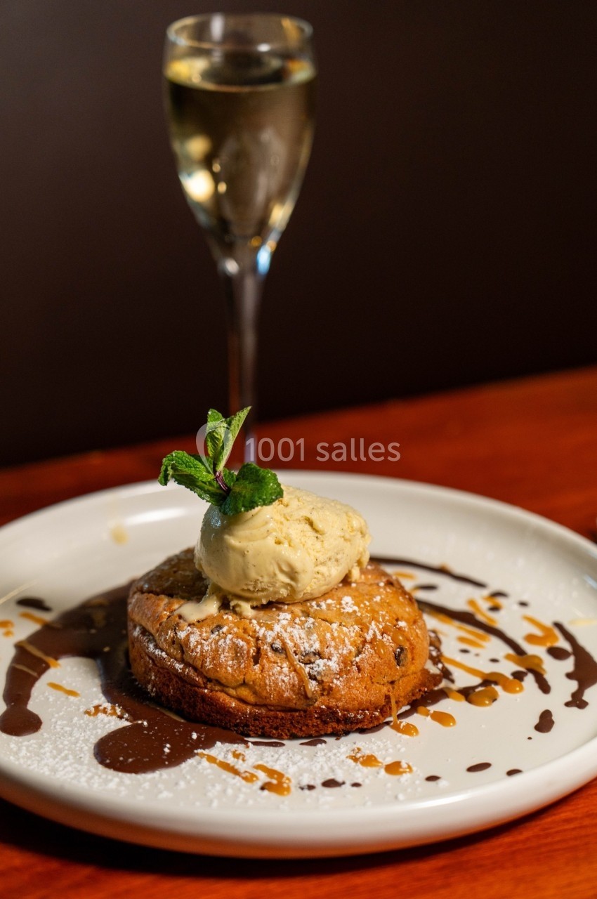 Dessert composé d'un biscuit chaud garni de glace à la vanille, décoré de chocolat et caramel, avec un verre de vin…
