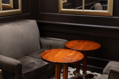 Table ronde en bois avec deux couverts, un verre d'eau et des condiments, entourée de fauteuils en cuir marron.