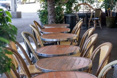 Table ronde en bois avec deux couverts, un verre d'eau et des condiments, entourée de fauteuils en cuir marron.