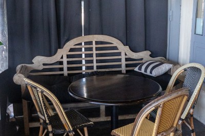 Table ronde en bois avec deux couverts, un verre d'eau et des condiments, entourée de fauteuils en cuir marron.