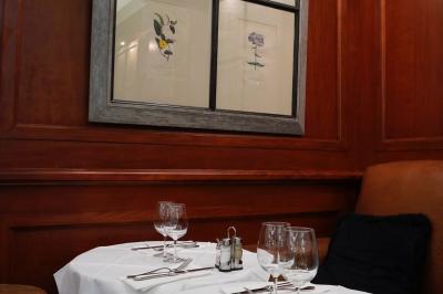 Terrasse extérieure avec tables dressées, nappes blanches, chaises en osier et végétation luxuriante en arrière-plan.