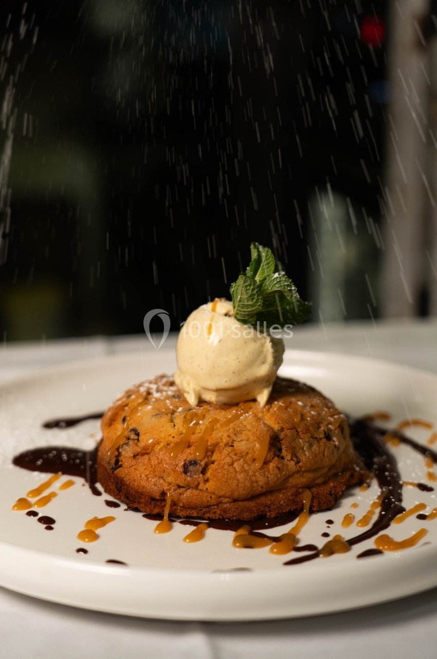 Cookie chaud garni d'une boule de glace vanille, décoré de caramel, chocolat et une feuille de menthe.