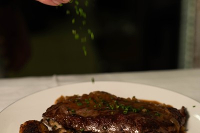 Un dessert crémeux garni de framboises et de menthe, avec un gâteau et une coupe de champagne en arrière-plan.