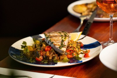 Un dessert crémeux garni de framboises et de menthe, avec un gâteau et une coupe de champagne en arrière-plan.