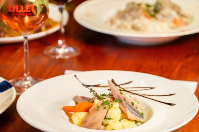 Un dessert crémeux garni de framboises et de menthe, avec un gâteau et une coupe de champagne en arrière-plan.