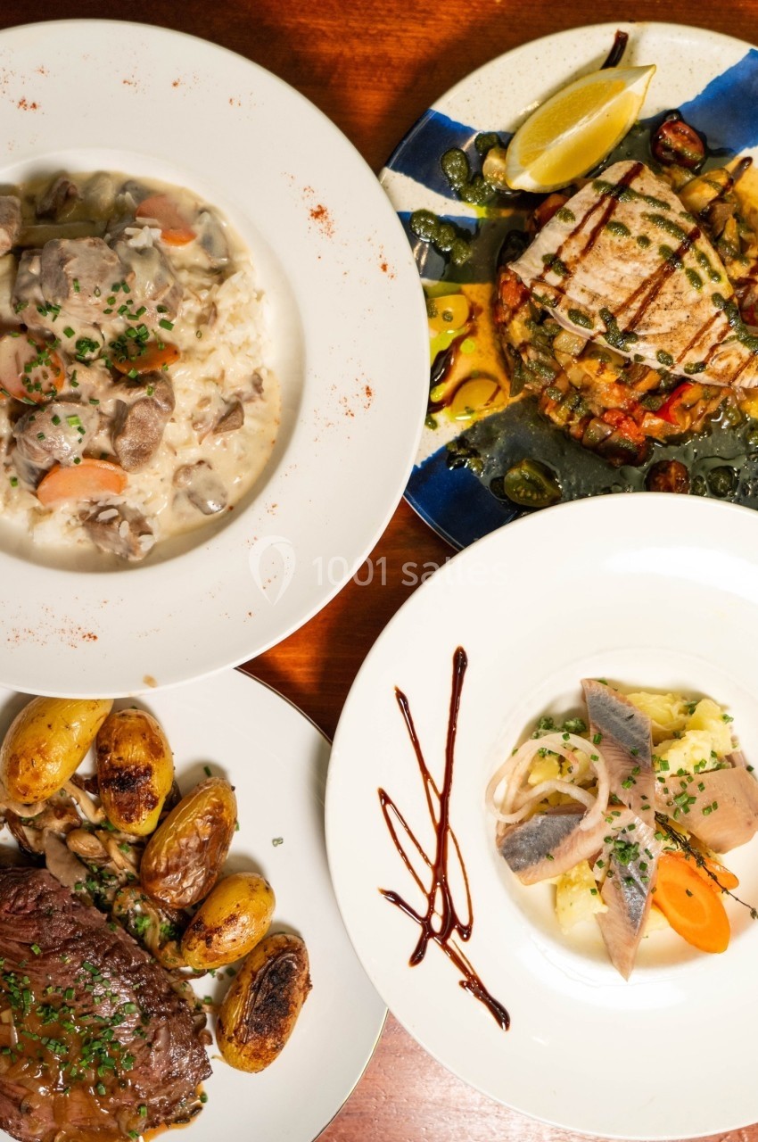 Quatre plats variés présentés sur une table en bois, comprenant viande, poisson, légumes et risotto.