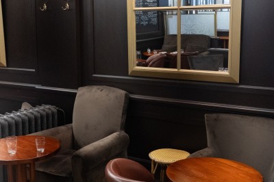 Salle de restaurant avec tables en bois, chaises assorties et grandes fenêtres laissant entrer la lumière naturelle.