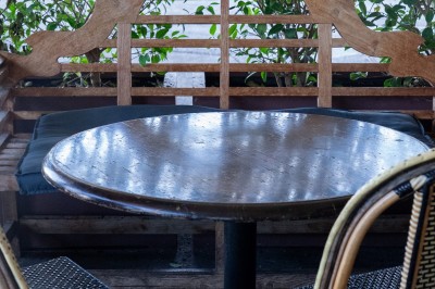 Salle de restaurant avec tables en bois, chaises assorties et grandes fenêtres laissant entrer la lumière naturelle.