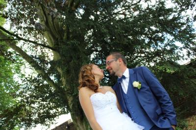 Un couple de mariés échange un regard complice devant l'autel d'une église ornée de bois sculpté.