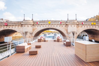 Bateau naviguant sur une rivière avec un groupe de personnes rassemblées sur le pont supérieur.