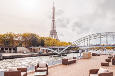 Bateau naviguant sur une rivière avec un groupe de personnes rassemblées sur le pont supérieur.