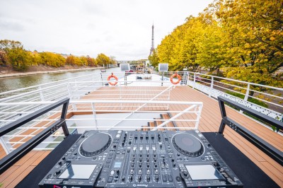 Bateau naviguant sur une rivière avec un groupe de personnes rassemblées sur le pont supérieur.