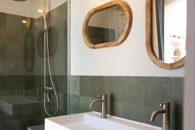 Salle de bain moderne avec douche à l'italienne, murs en carreaux verts, double vasque et miroirs en bois.