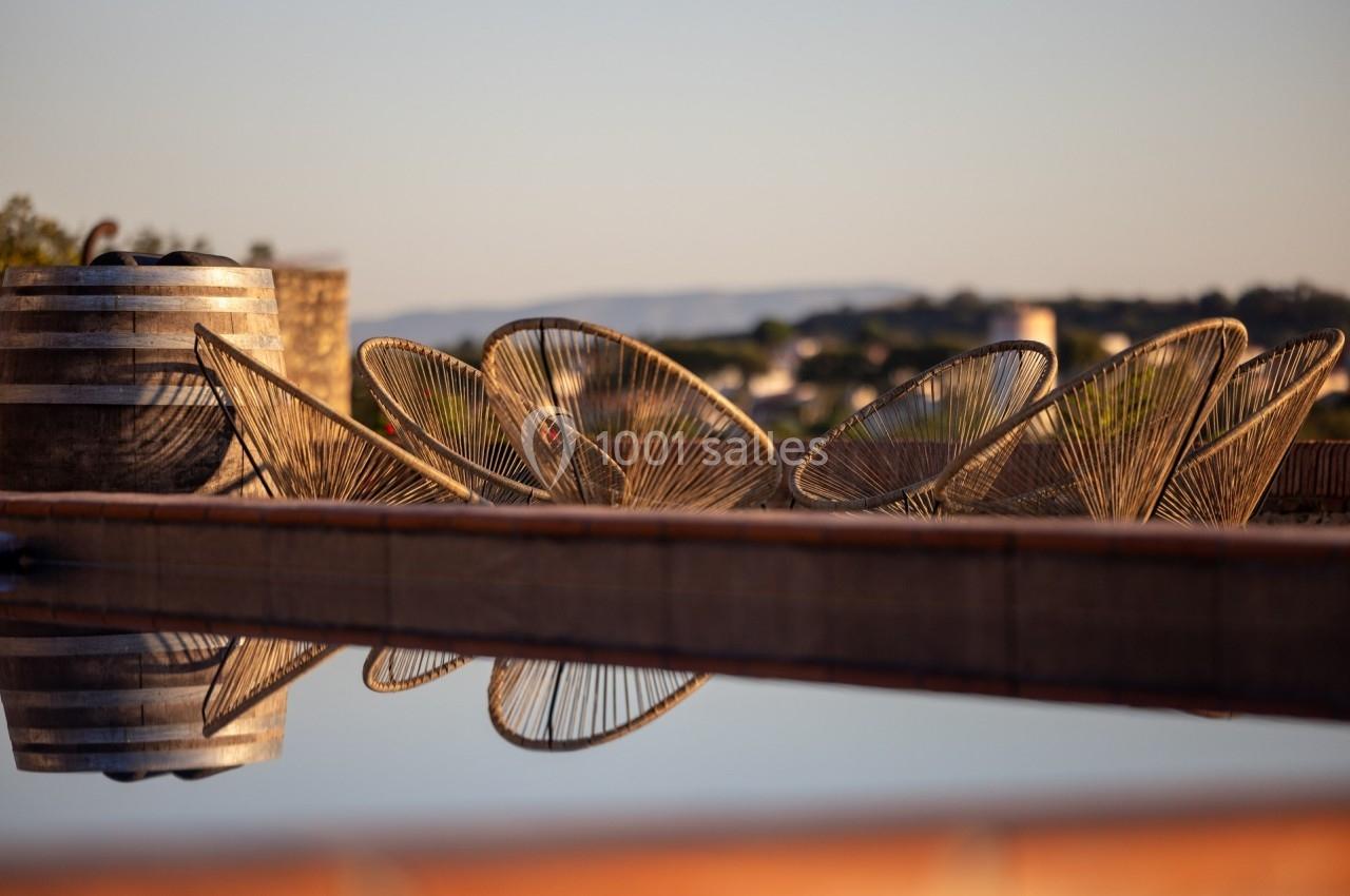 Chaises en métal design disposées près d'une piscine, avec un paysage flou en arrière-plan au coucher du soleil.