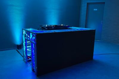 Terrasse en bord de mer avec tables et chaises blanches, vue sur la plage, la mer et un écran affichant une publicité.